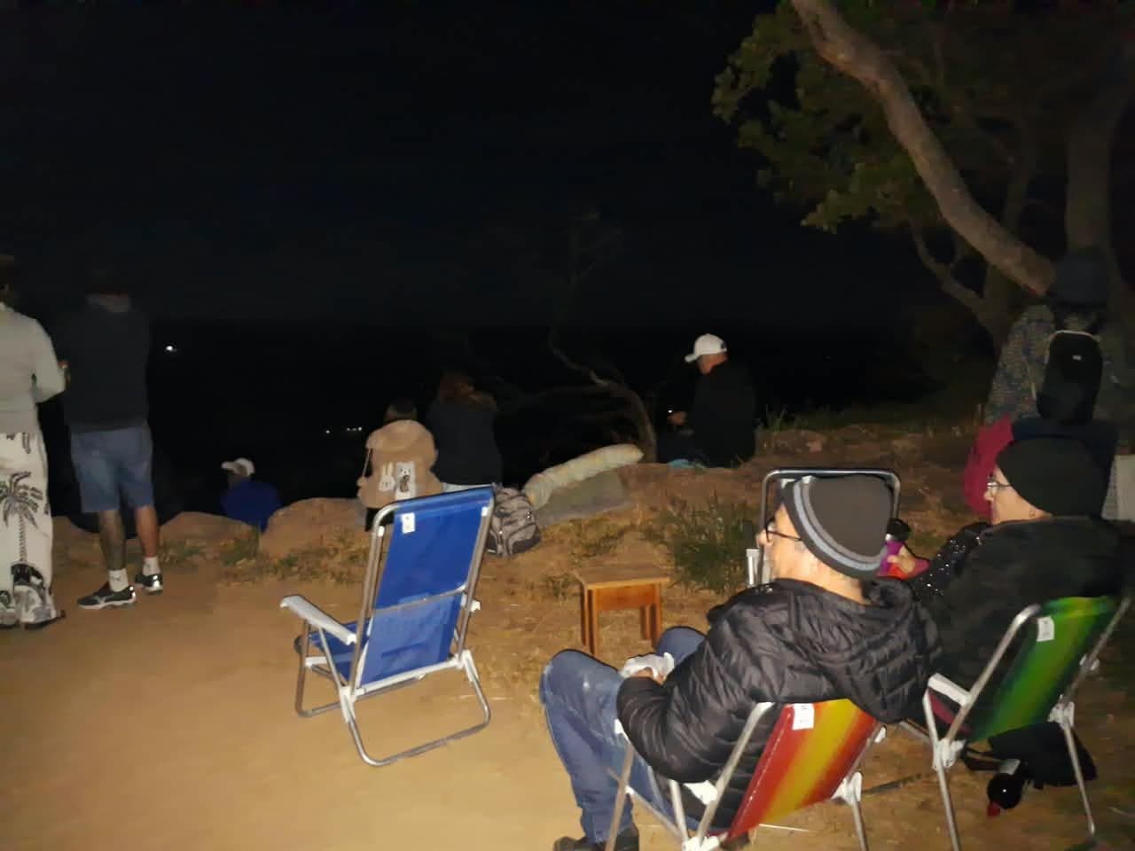 Participantes em cadeiras de praia no platô, de noite, durante uma vigília